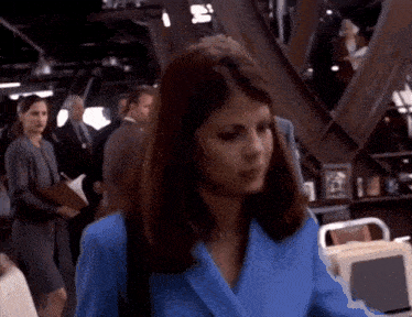 a woman in a blue suit is walking in a crowd