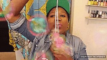 a woman with a green hat is drinking cotton candy through a straw ..