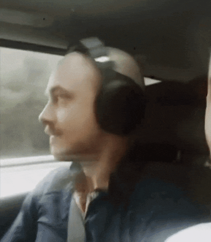 a man in a car wearing headphones looks out the window