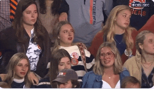 a group of people sitting in a stadium with one wearing a shirt that says " tigers "