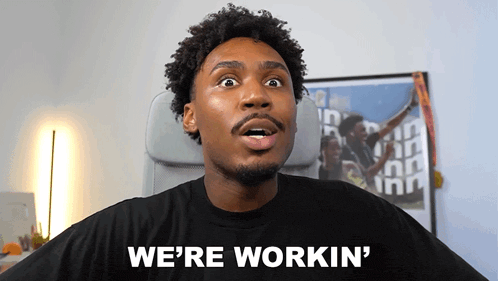 a man says we 're workin ' in front of a poster