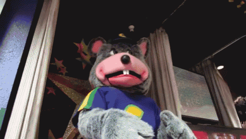 a chuck e cheese mascot is standing in front of a screen