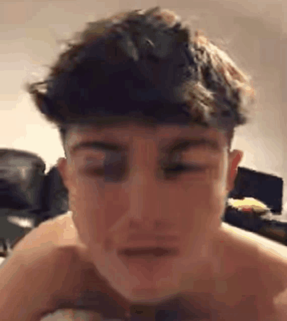 a man without a shirt is making a funny face while laying on a bed .