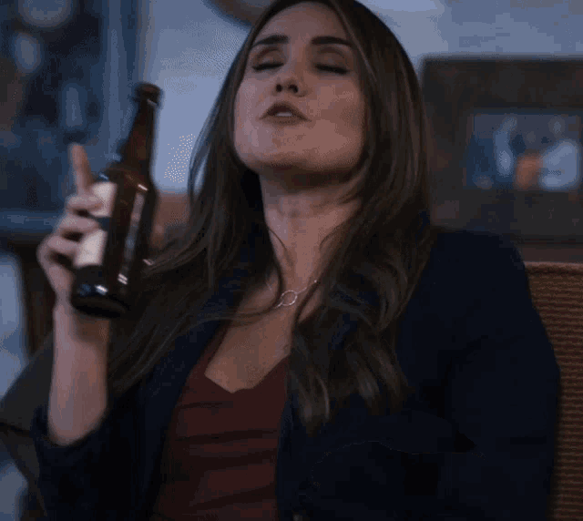 a woman is holding a bottle of beer in her right hand
