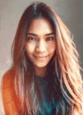 a woman with long brown hair is smiling and wearing a blue shirt