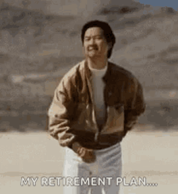 a man is standing in the desert with his hands in his pockets and smiling .