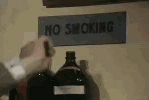 a no smoking sign is above a bottle of alcohol