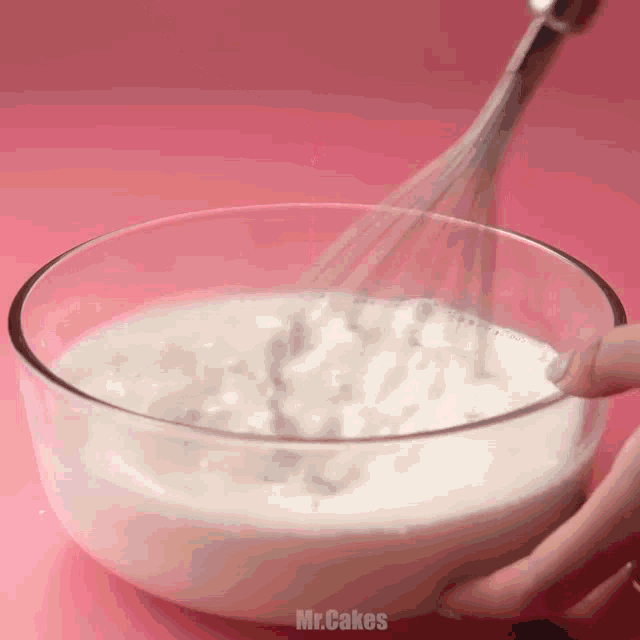 a person is mixing something in a glass bowl with a whisk and the words mr.cakes written on the bottom