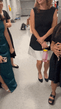 a woman in a black dress has a pink water bottle in her hand