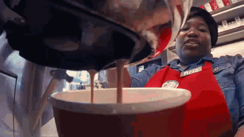 a woman wearing a red apron with the word maid on it is pouring something into a bowl