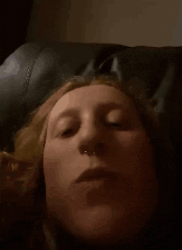 a close up of a woman 's face with a nose ring laying on a couch .