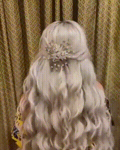 a woman with long white hair is standing in front of a curtain wearing a headpiece .