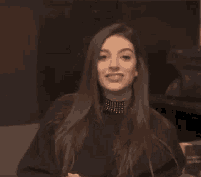 a woman in a black sweater is clapping her hands in a dark room .