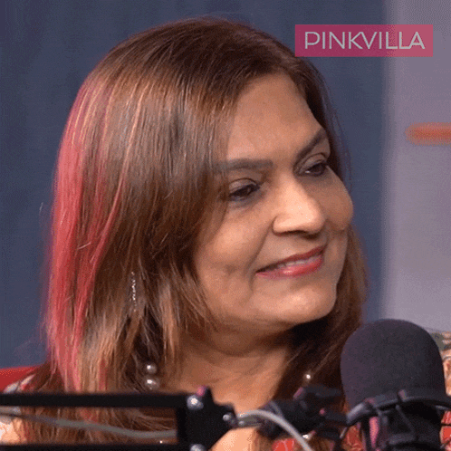 a woman is smiling in front of a microphone with a pinkvilla logo in the background