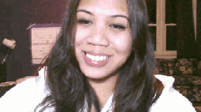 a woman with long hair is smiling in front of a purple wall calendar