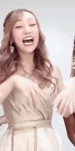 a woman in a white dress is laughing with her mouth open while holding another woman 's hand .