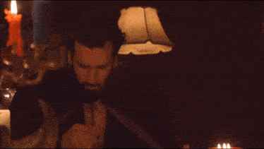 a man with a beard is sitting in front of a lamp in a dark room
