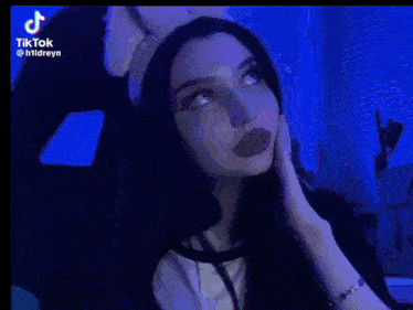 a woman wearing a cat ear headband is making a peace sign with her hands .