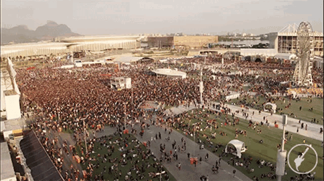 a large crowd of people are gathered in a field with a ferris wheel in the background