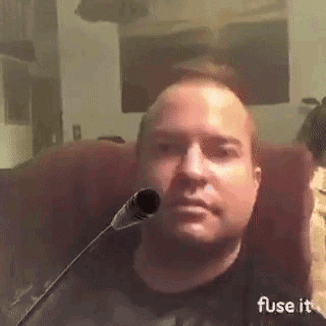 a man is sitting in a chair with a microphone in front of his mouth .