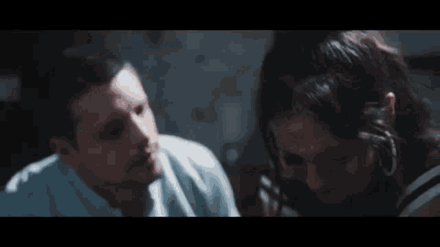 a man and a woman are sitting next to each other looking at something .
