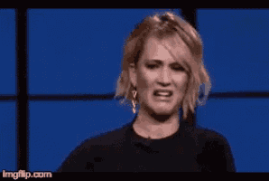 a woman is making a funny face while standing in front of a blue wall .