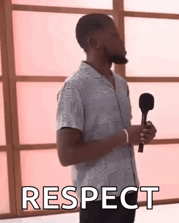 a man with a beard is holding a microphone and saying `` respect '' .