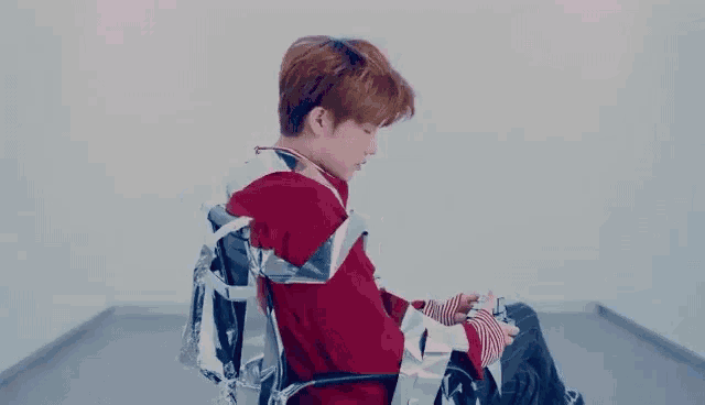a young man in a red sweater is sitting in a wheelchair wrapped in aluminum foil .