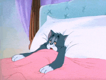 a cartoon cat is laying in a bed with a pink blanket