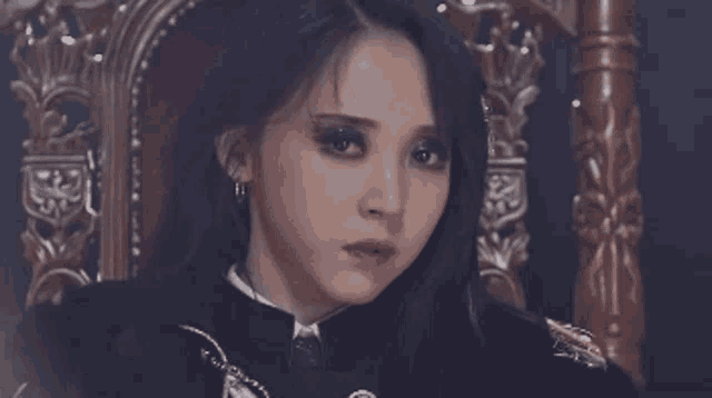 a woman is sitting in a chair with her eyes closed and looking at the camera .
