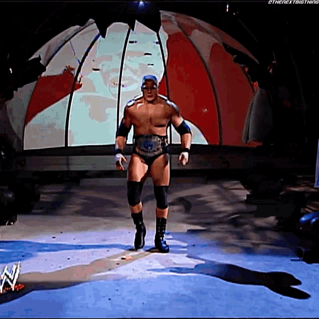 a man in a wrestling outfit is walking on a stage with a wwe logo in the foreground