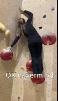 a woman is climbing a climbing wall with the words ok nevermind written below her