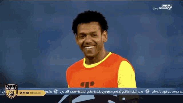 a soccer player is smiling in front of a screen that says ' live '