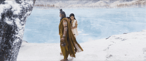 a man and two women are walking in the snow near a lake