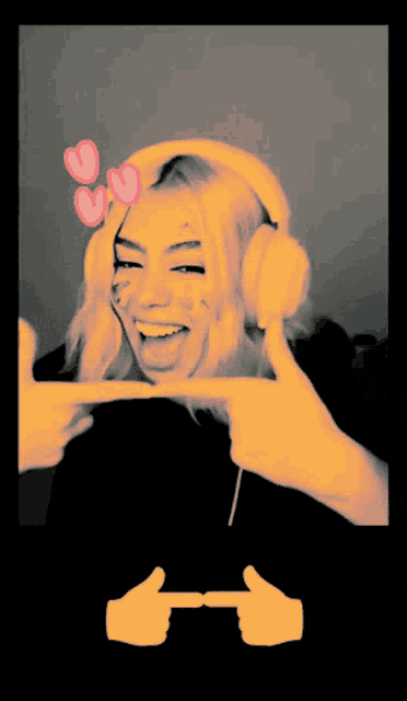 a woman wearing headphones is smiling and pointing at herself