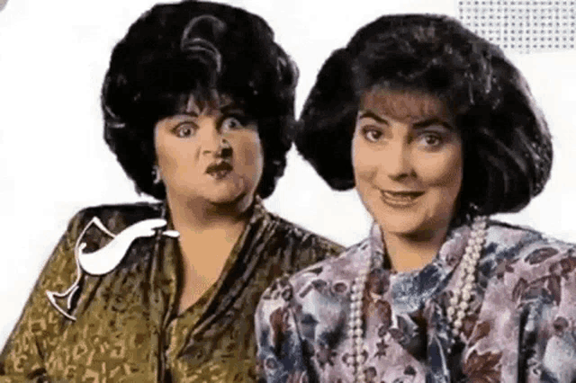 two women wearing wigs and pearls are standing next to each other and making funny faces .