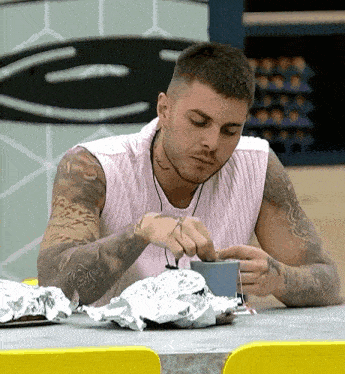 a man with a tattoo on his arm is sitting at a table with a cup of coffee