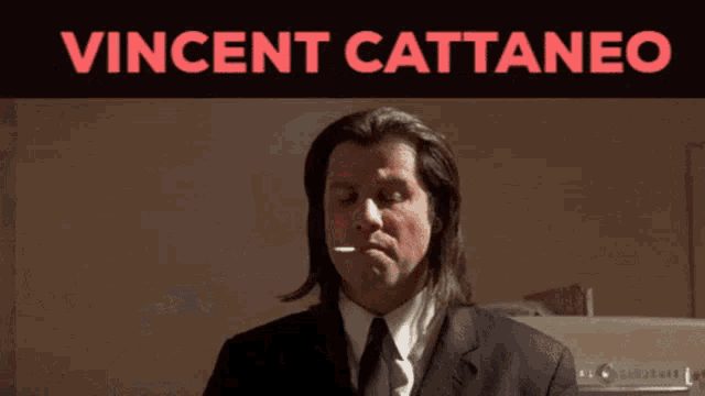 a man in a suit and tie is standing in front of a sign that says vincent cattaneo on it
