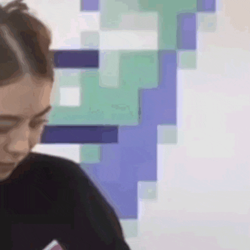a woman is sitting in front of a wall with blue and green squares on it .