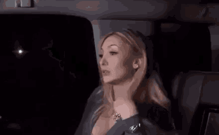 a woman is sitting in the back seat of a car with her hand on her face .