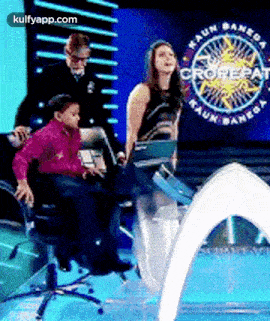 a boy is sitting in a chair while a woman stands on a stage .
