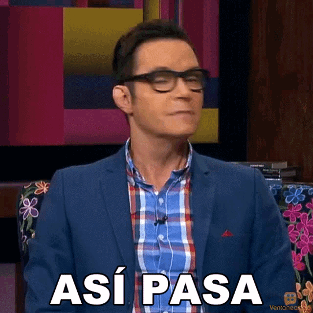 a man wearing glasses and a blue suit says " asi pasa "
