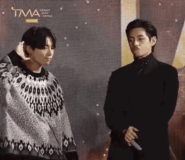two young men are standing next to each other on a stage .