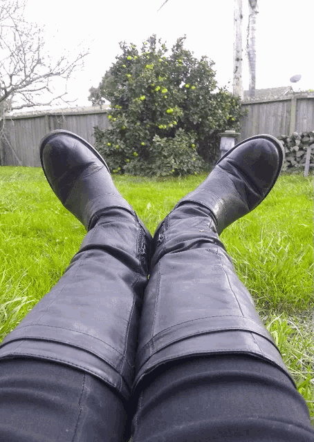 a person wearing black boots is laying on the grass