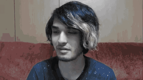 a man with a beard and long hair is sitting on a red couch .