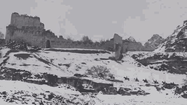 a black and white photo of a snowy mountain with a castle in the background