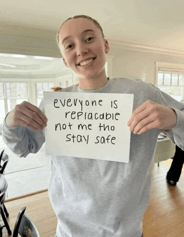 a girl holds a sign that says everyone is replaceable not me tho stay safe