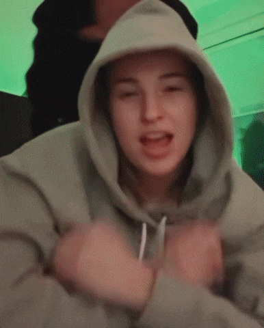 a woman wearing a hoodie is making a funny face with her eyes closed