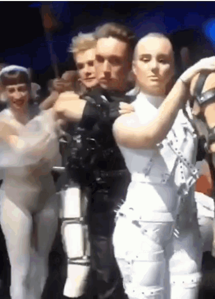 a group of people are standing in a line and one of them has a mask on