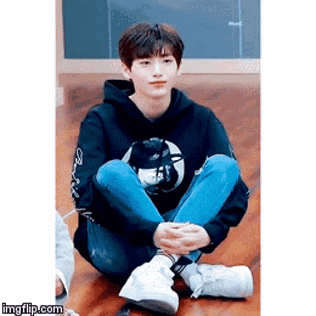 a young man is sitting on the floor with his legs crossed
